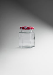 Frasco hexagonal de vidrio transparente con tapa roja uso alimenticio 85 ml — imagen de producto