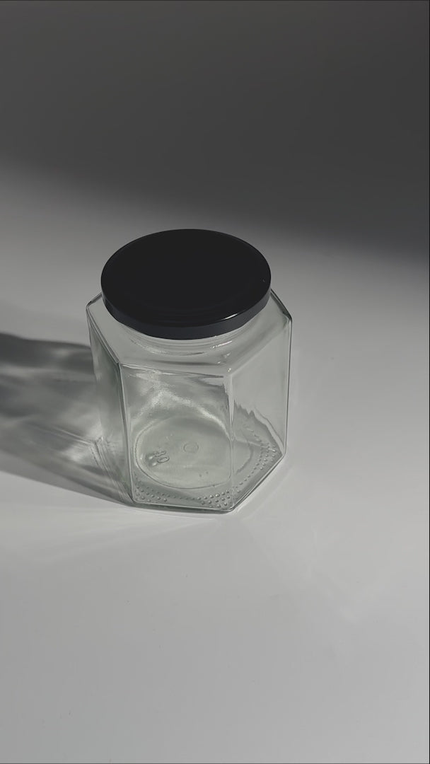 Frascos hexagonales de vidrio transparente con tapa negra uso alimenticio de 45 a 500 ml — video de producto